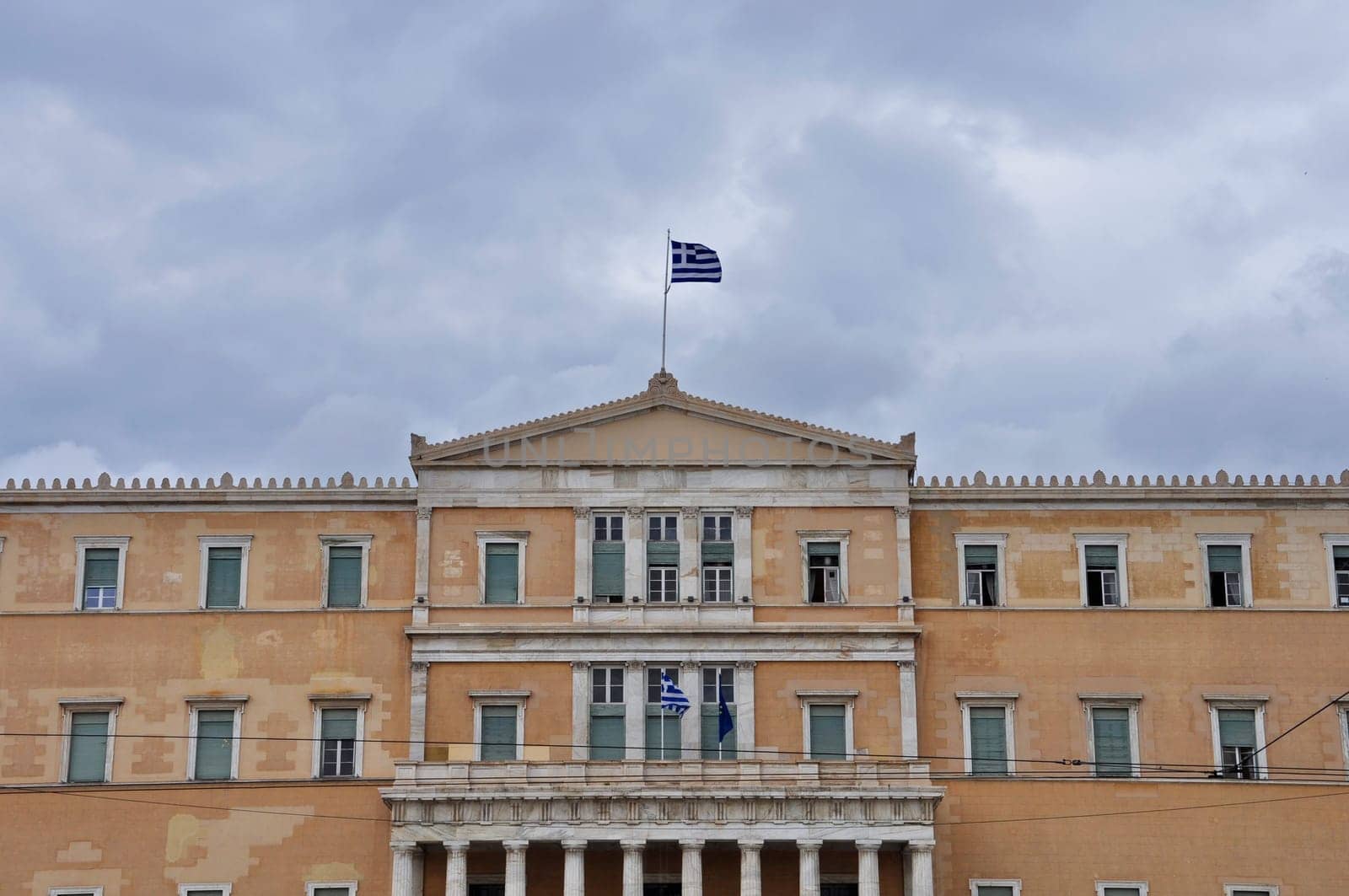 Hellenic parliament neoclassical building facade under cloudy sky. Athens, Greece.