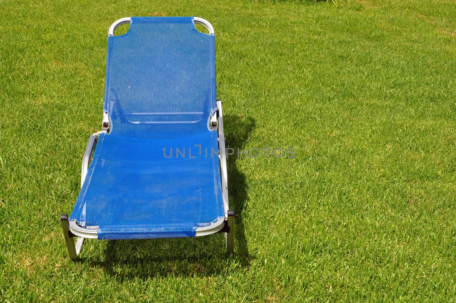 Lawn chair on green grass background. Garden furniture.