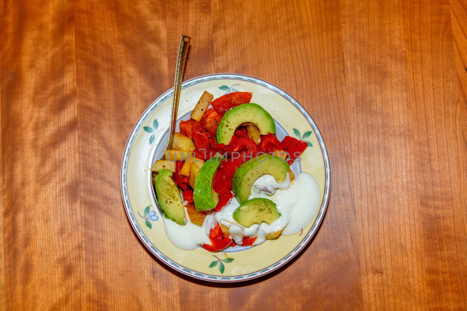 plate with fried vegetables and row avocado on wooden ground