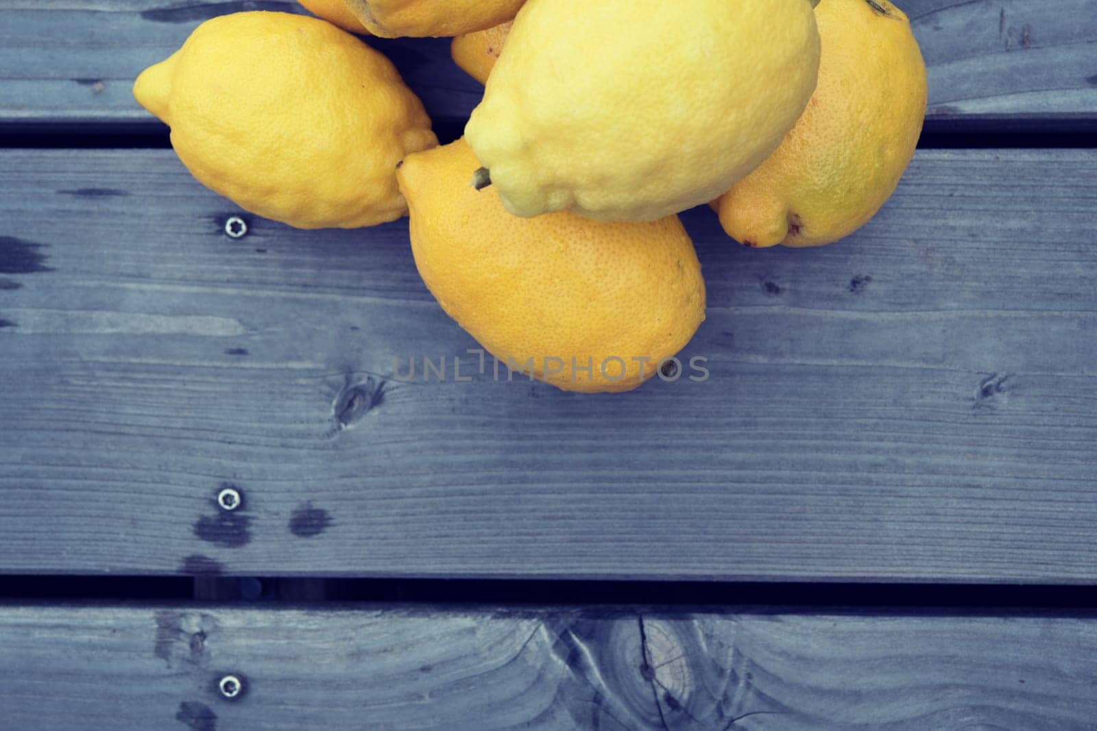 pile of yellow lemons on wooden ground