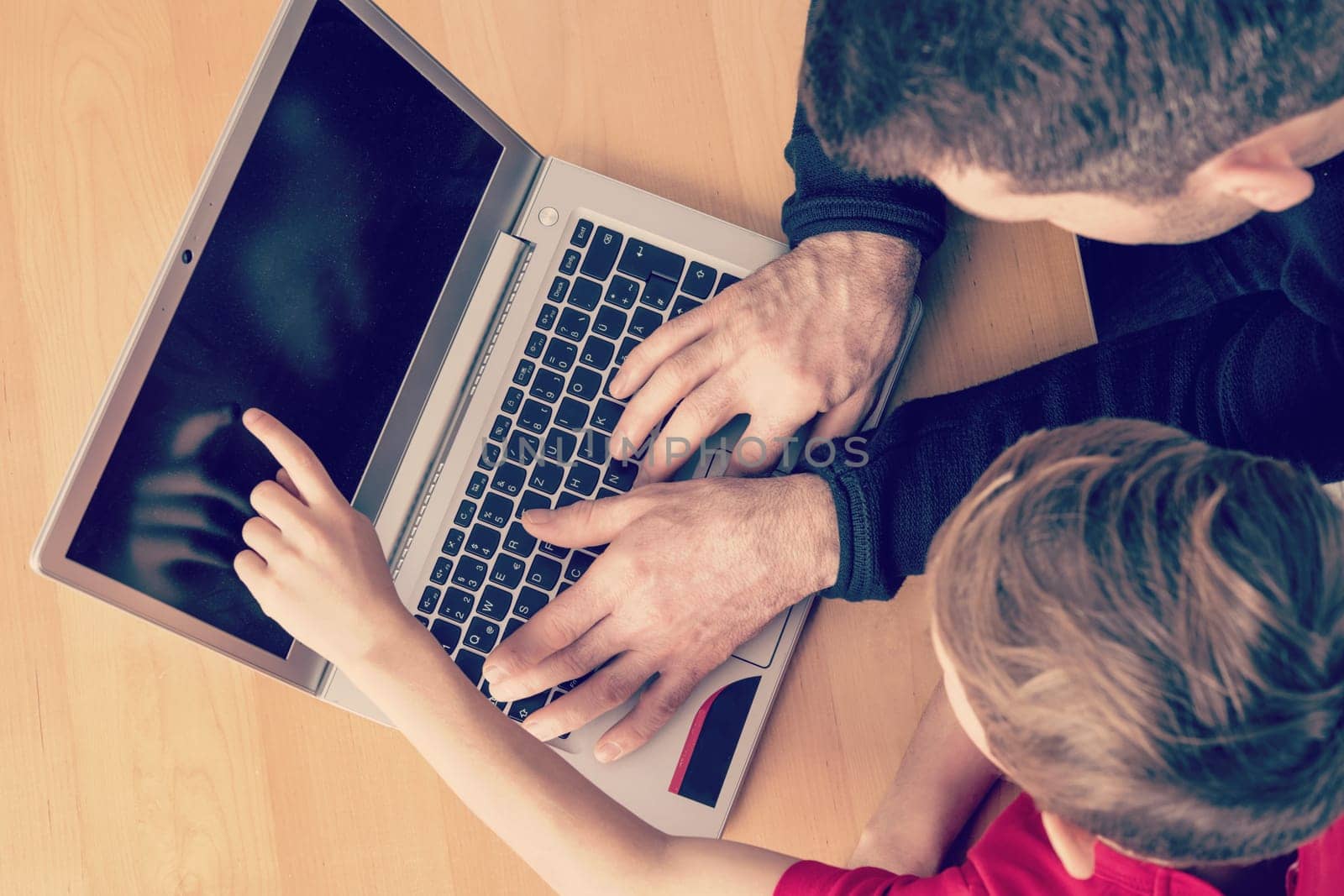 father and son using computer togetherat home