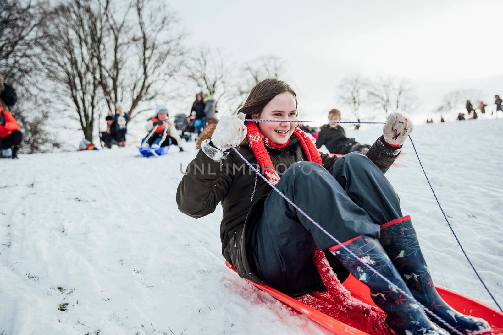 Close up shot of a little girl on a snow sled in a community race.