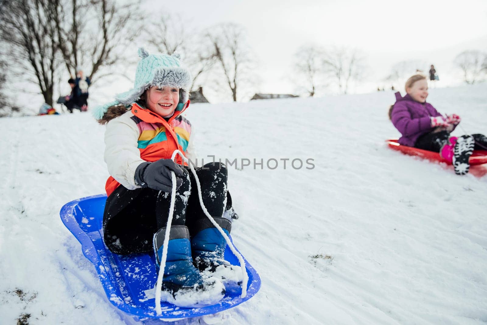 Close up shot of a little girl on a snow sled in a community race.