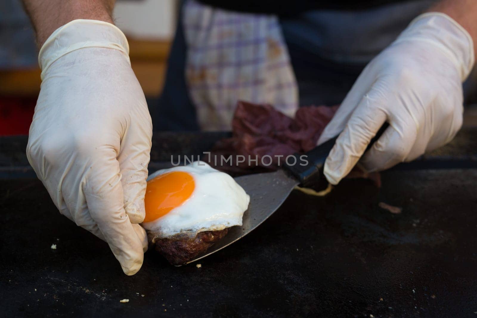 Chef making beef burgers outdoor on open kitchen international food festival event. Street food ready to serve on a food stall.