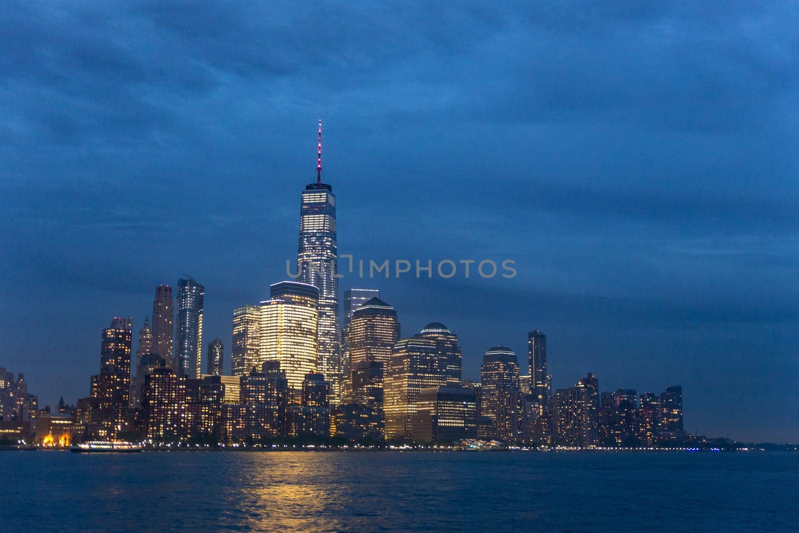 Panoramic view of Lower Manhattan from Ellis Island at cloudy dusk, New York City.