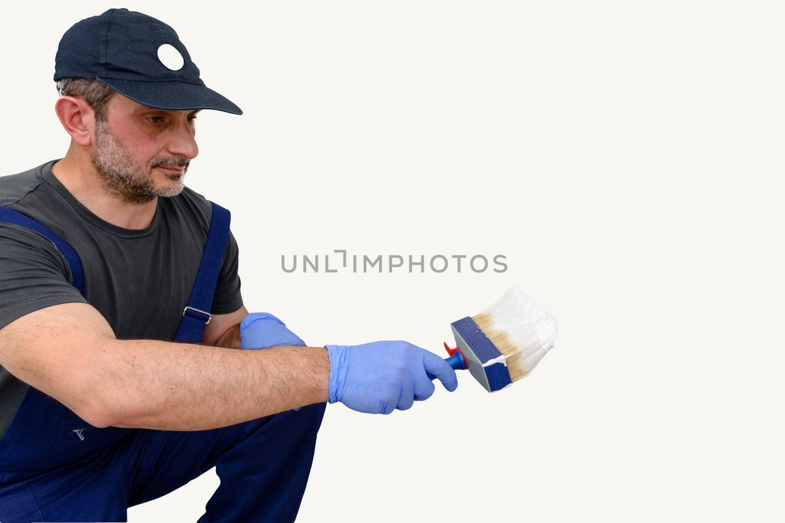 Painter paints the wall with the tint of white. Wall with serious moisture problems. Detail of the brush. white dye is prepared for the painter's job.