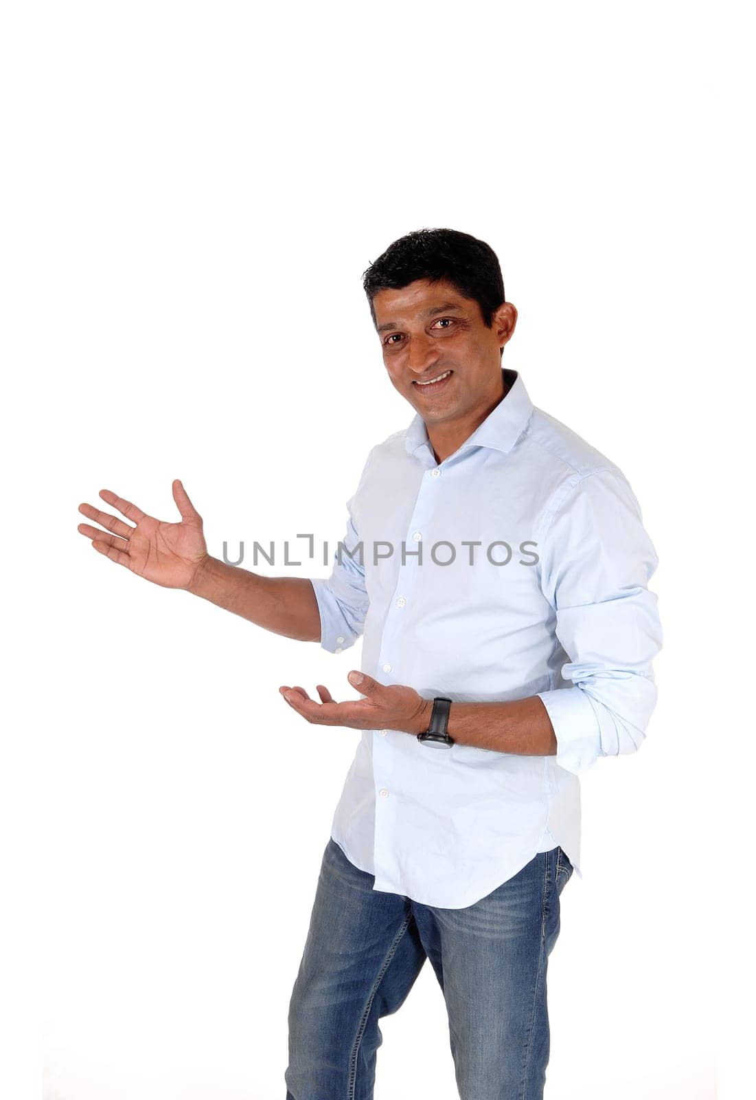 A good looking East Indian man standing in jeans and light blue.shirt with hands outstretched, isolated for white background.