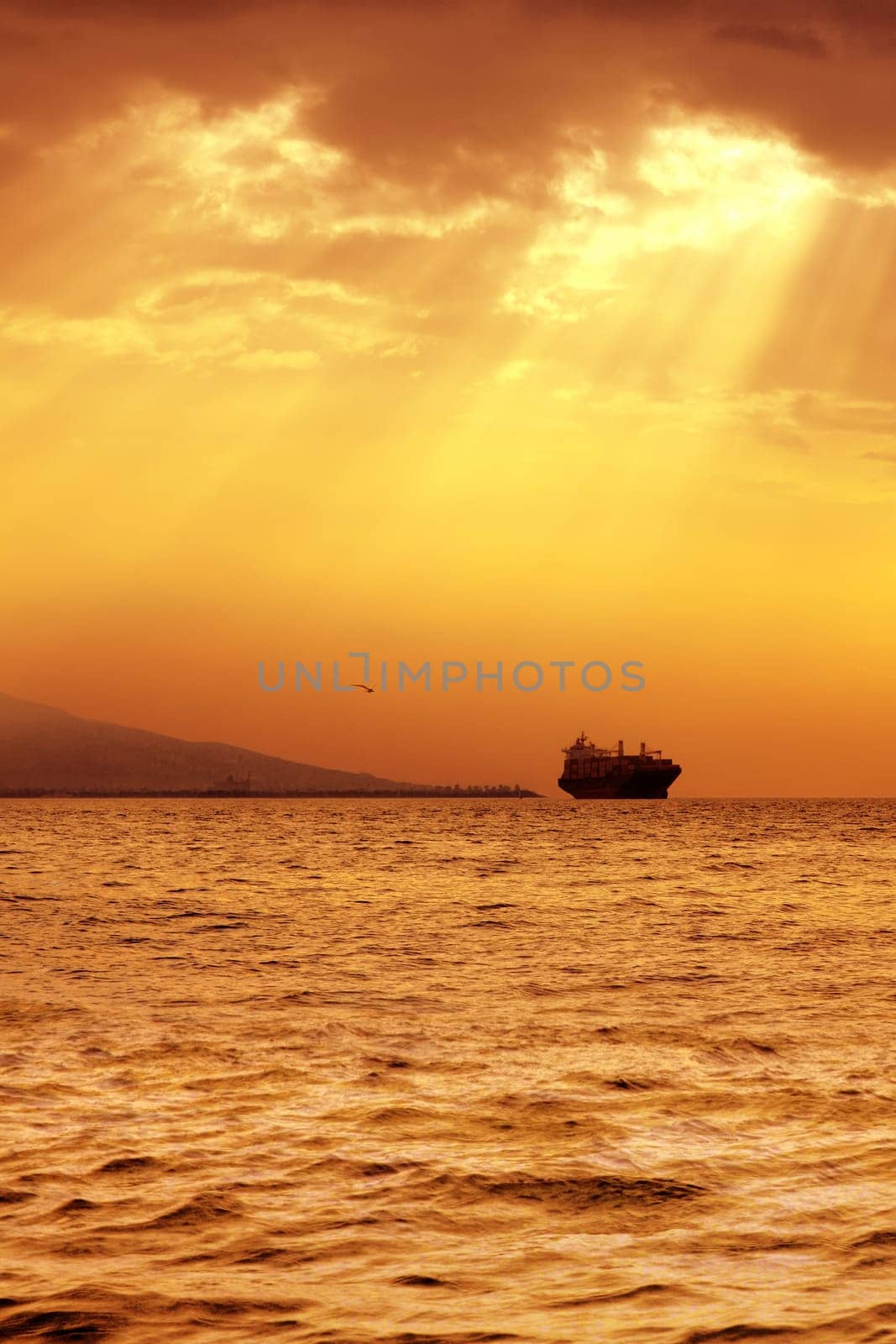 seascape image of cargo ship over sunset