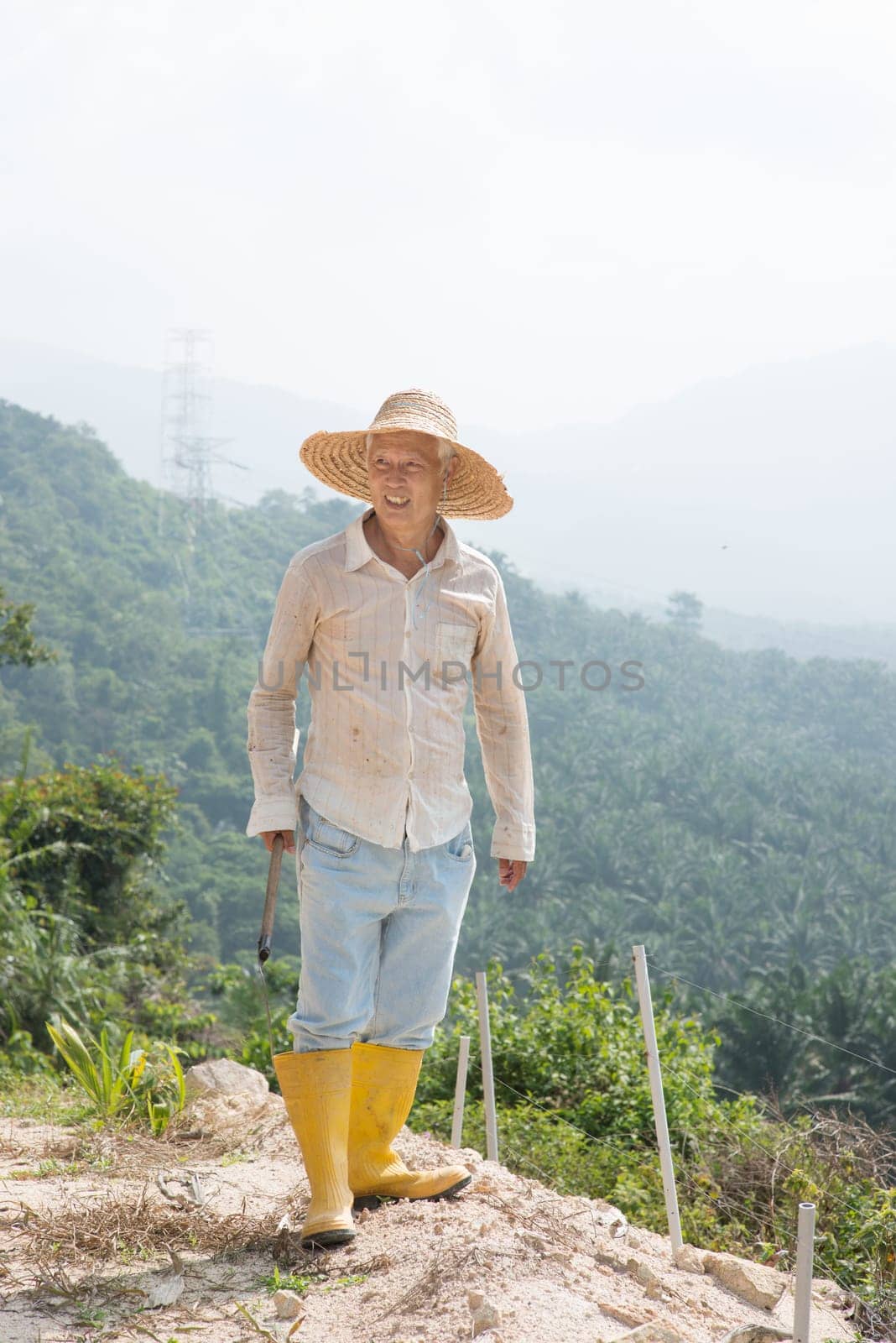 Asian worker cleaning land under hot sun.