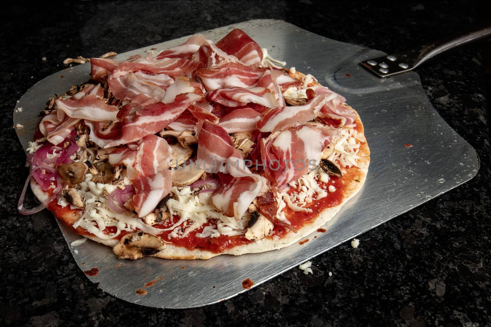 Pizza with bacon and mushrooms just before being baked in the oven