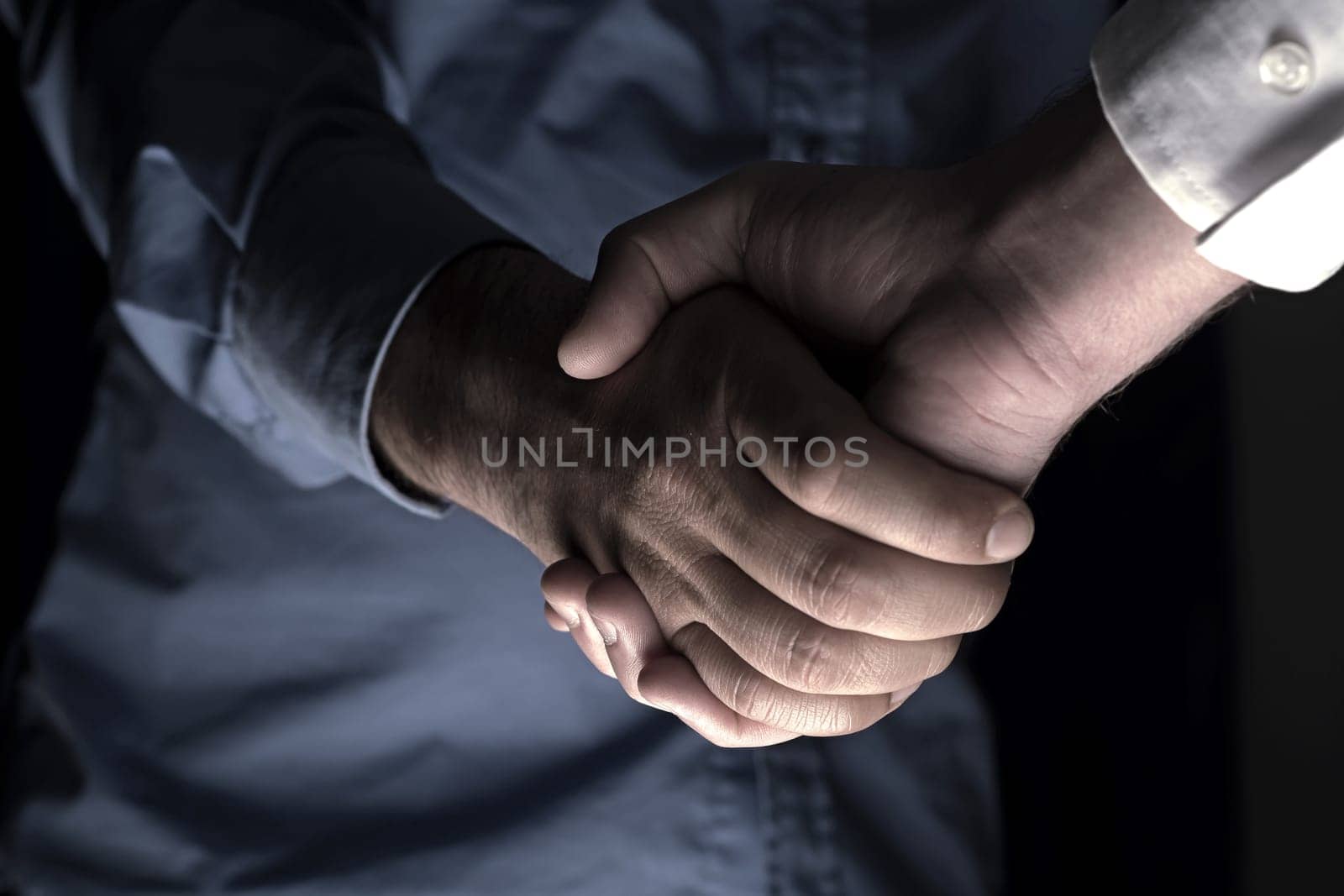 Handshaking of two business people. Partnership - Teamwork. Greeting, Form Of Communication. Light in scene come from down.