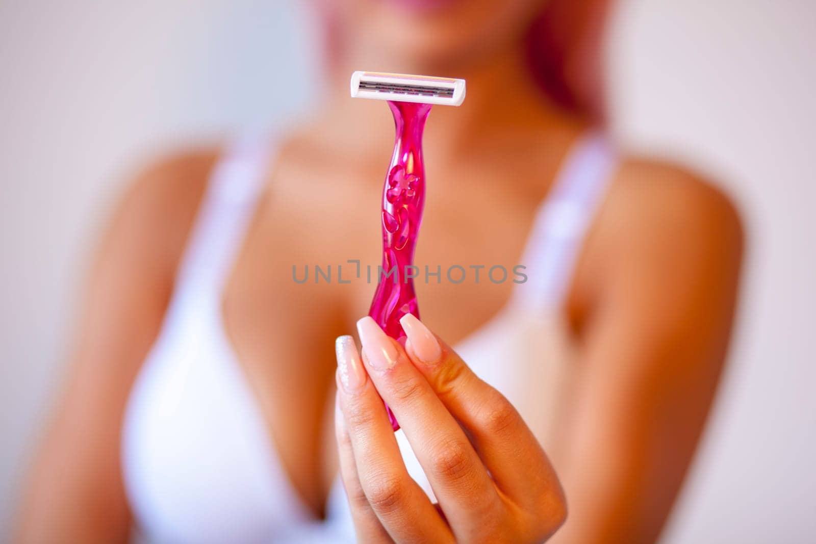 Attractive pink hair young woman hold and showing shaver razor for epilation hair removal with ergonomic pink holder. Body care skincare beauty concept