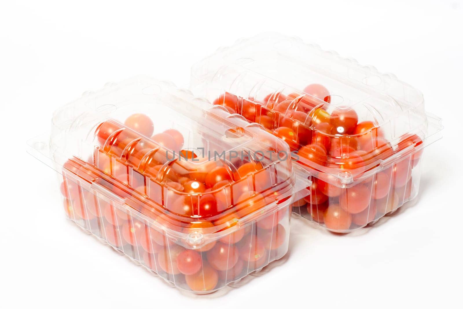 Cherry tomato in plastic cointainer packed and ready for market. Package of 500g, studio shoot on white