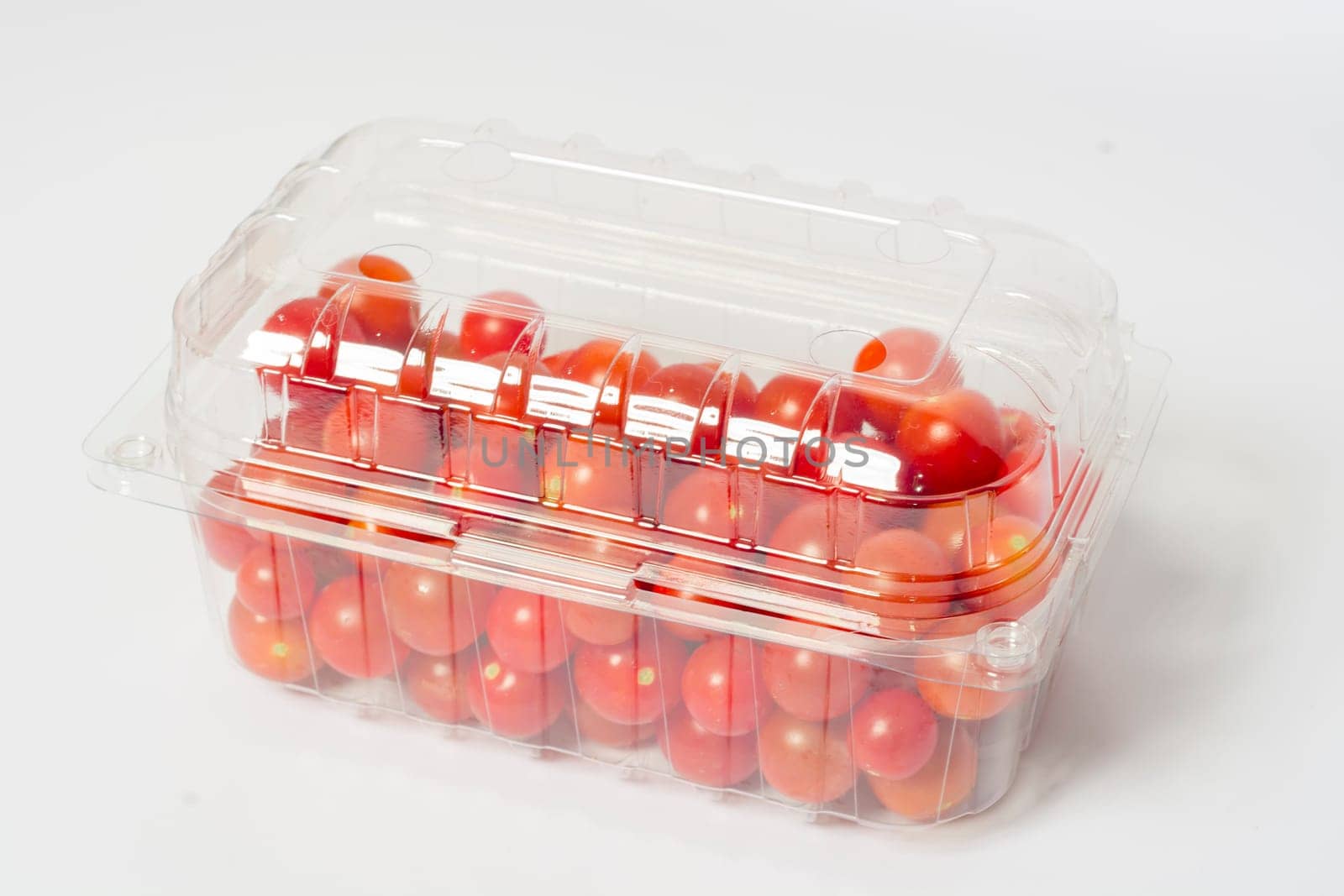 Cherry tomato in plastic cointainer packed and ready for market. Package of 500g, studio shoot on white