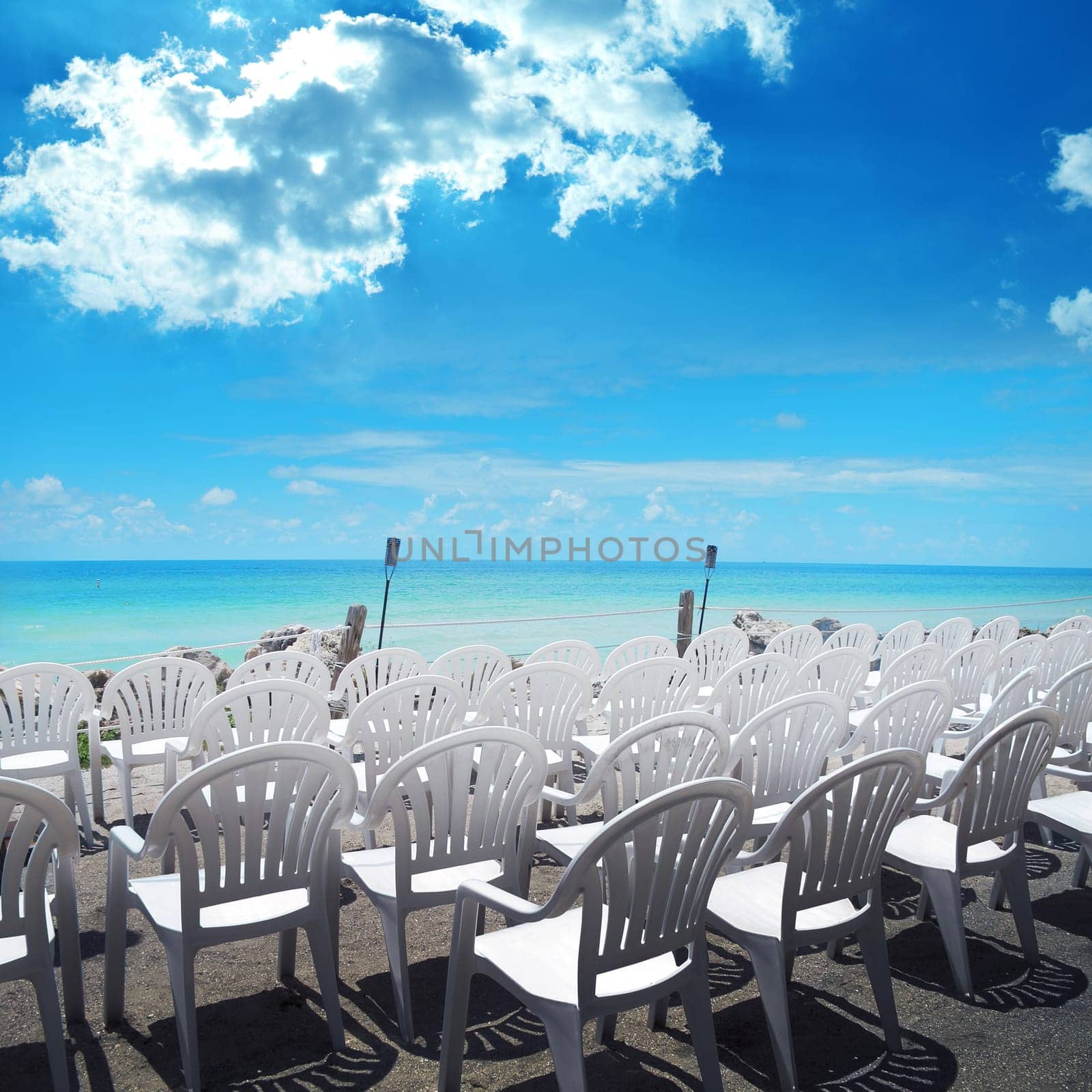 empty white chairs in a row at beach