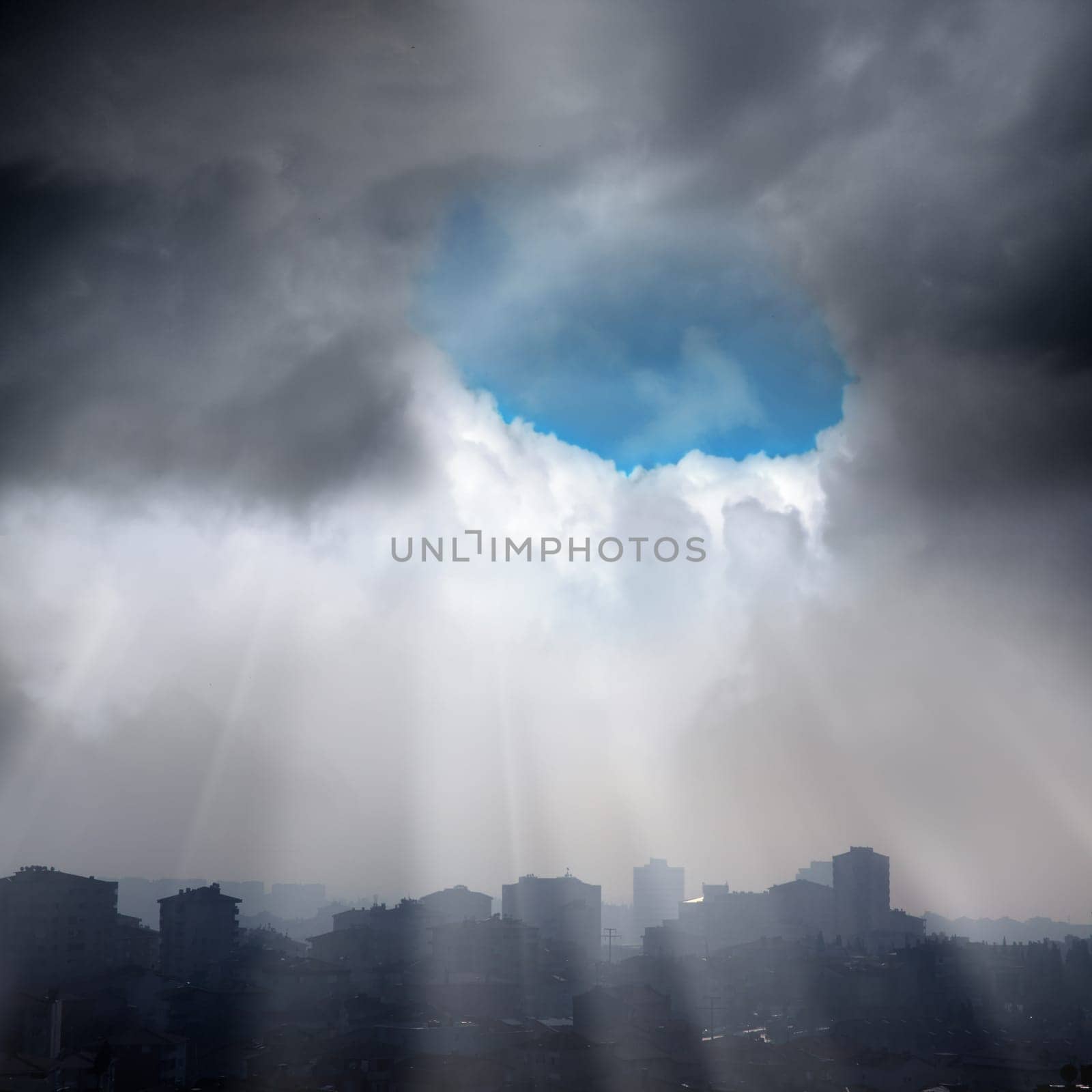 elevated view of city over cloudy sky and sun beams