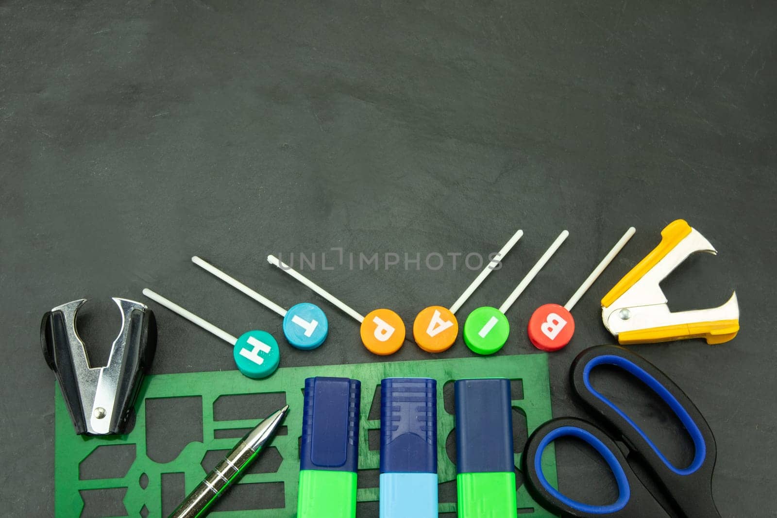 Closeup of colorful school supplies with copy space on blackboard background. Back to school.