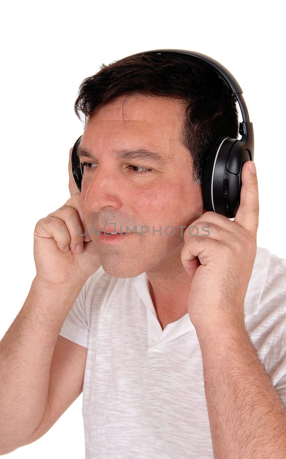 A good looking man sitting with his headphones on and.listening to music, isolated for white background.