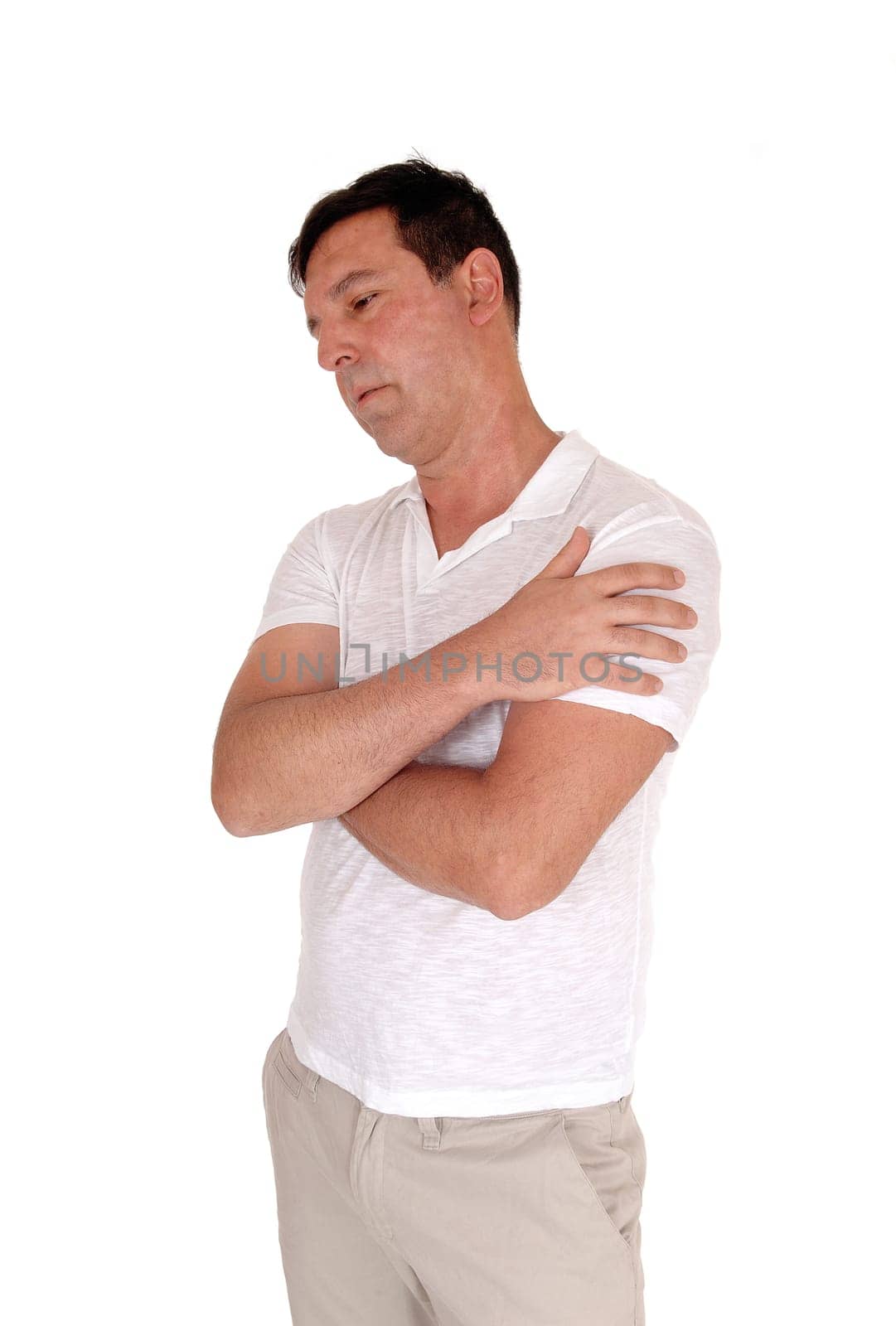 A tall handsome middle age man standing in a beige slacks and white.t-shirt with his arms crossed, isolated for white background.