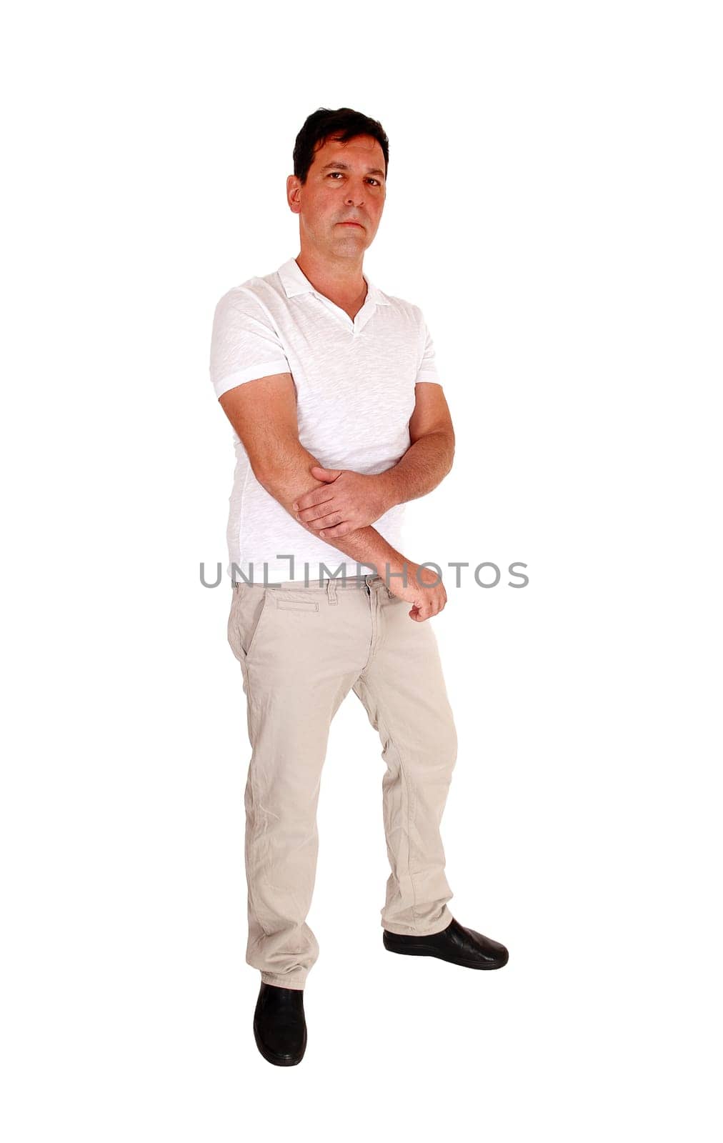 A tall handsome middle age man standing in beige slacks and white.t-shirt looking serious, isolated for white background.