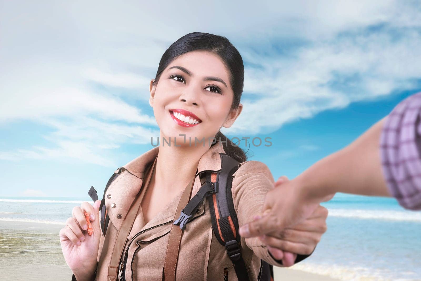 Smiling asian woman following her husband on vacation in the beach