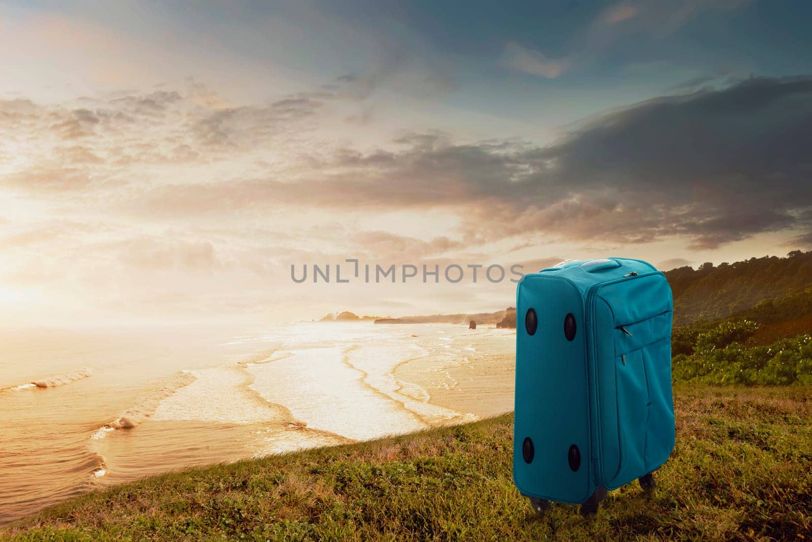 Blue suitcase on the cliff with seascapes view. Summer travel concept