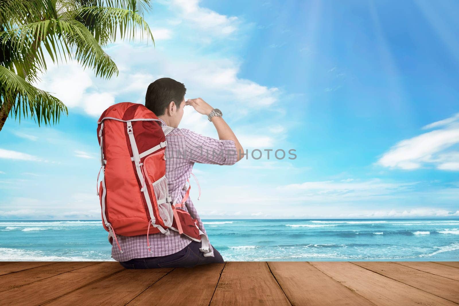 Young asian tourist man sitting and looking at seascape on the pier