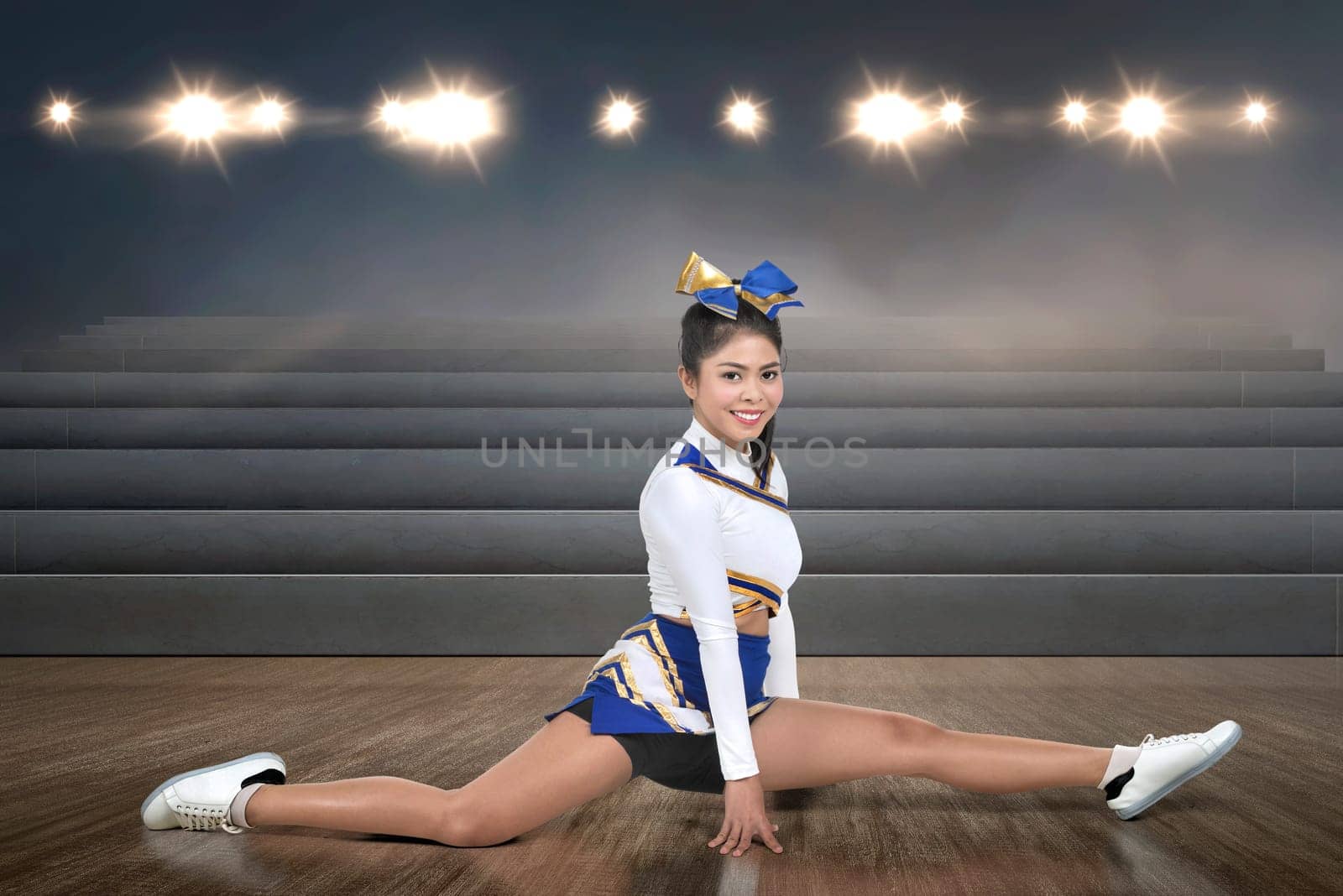 Smiling asian cheerleader doing splits at indoor arena
