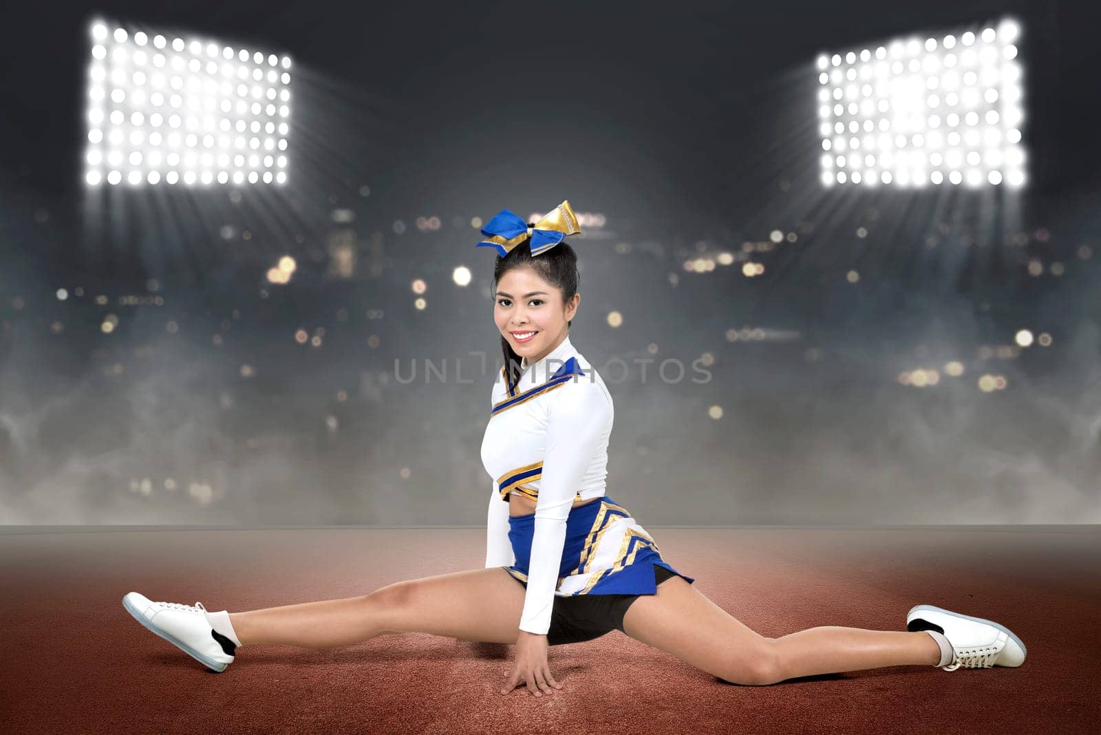 Beautiful asian cheerleader doing splits with spot lights background