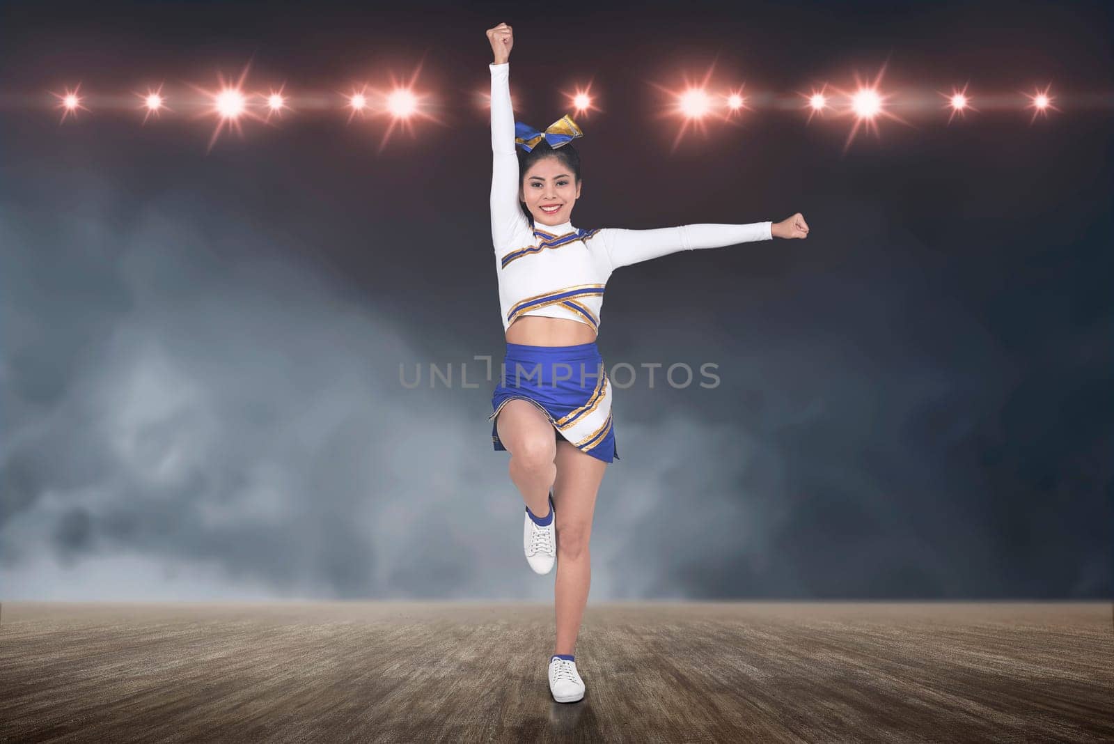 Beautiful asian cheerleader in action with spotlights on background