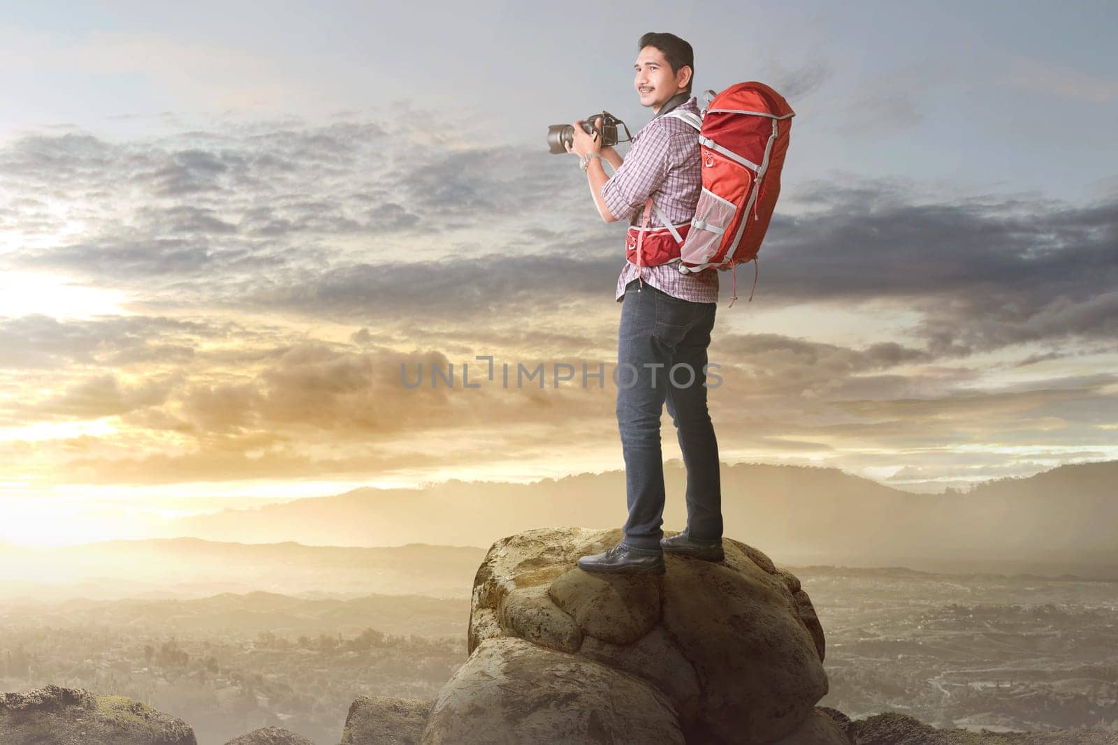 Happy asian tourist with camera and backpack ready to take a photo on the mountain
