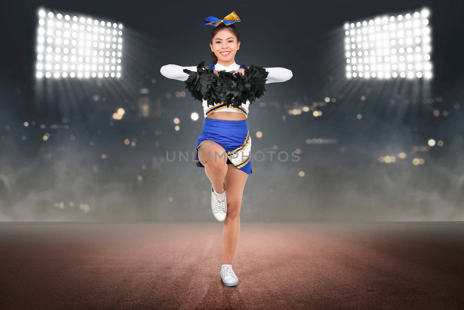 Young asian cheerleader in action with pom poms with spot light background