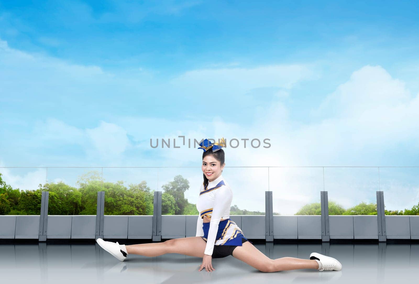 Smiling asian cheerleader doing splits in the building