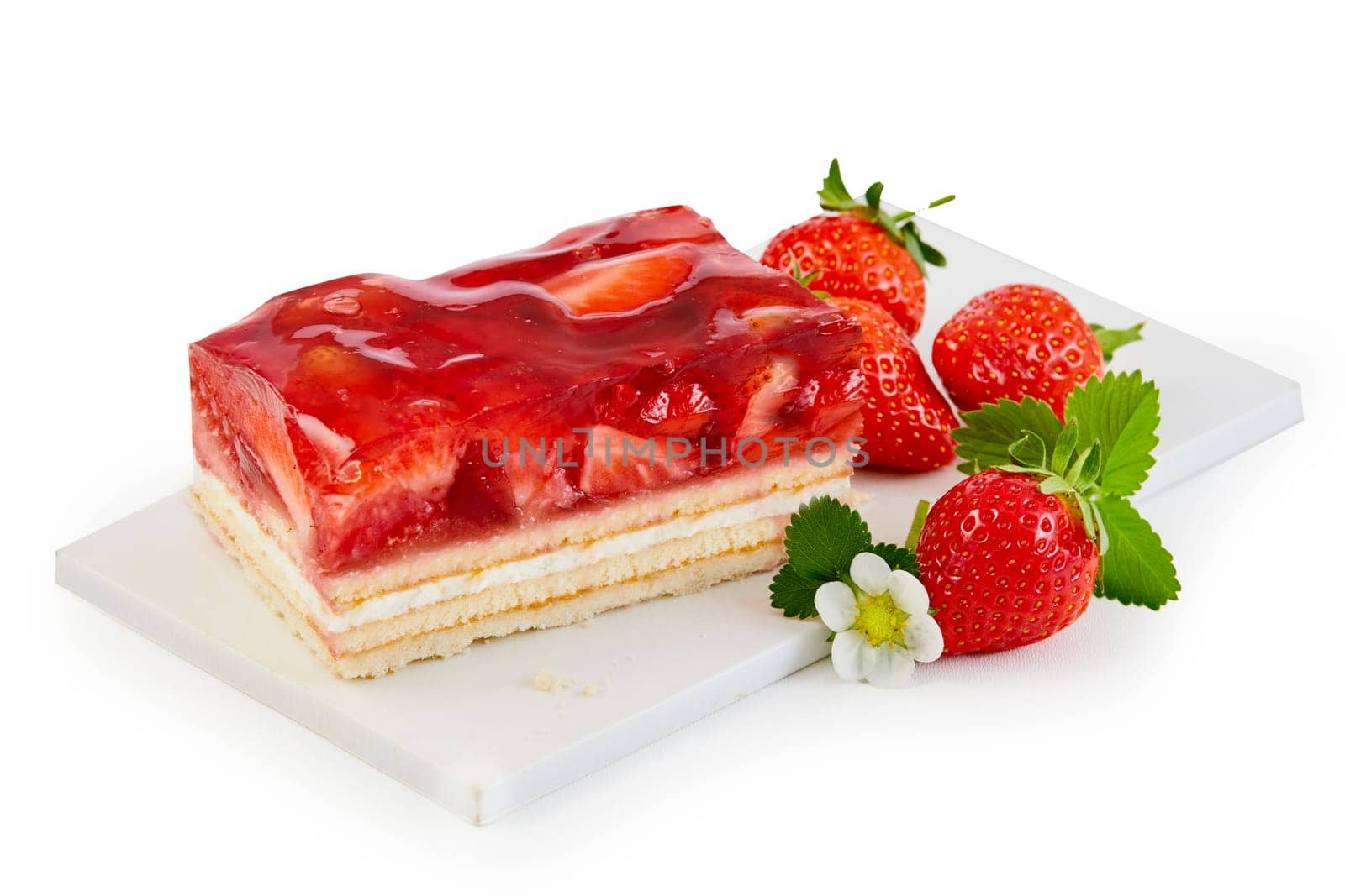 Delicious freshly baked layer cake topped with strawberries served on a white board with fresh whole fruit isolated on white
