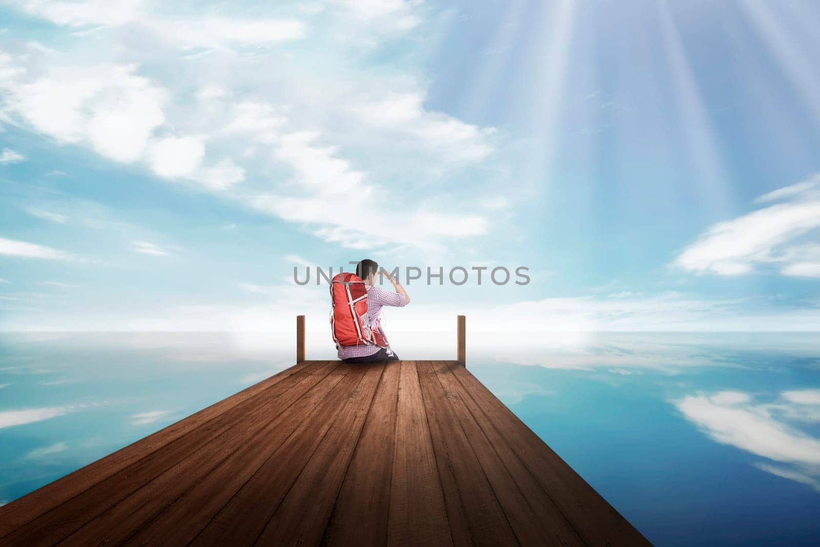 Attractive asian traveler man sitting and enjoying view from the dock