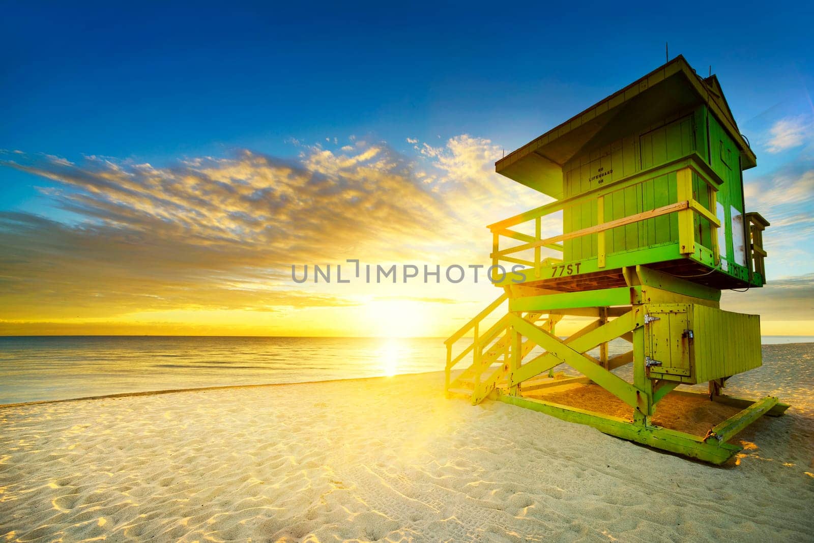 Miami South Beach sunrise with lifeguard tower and coastline with colorful cloud and blue sky.