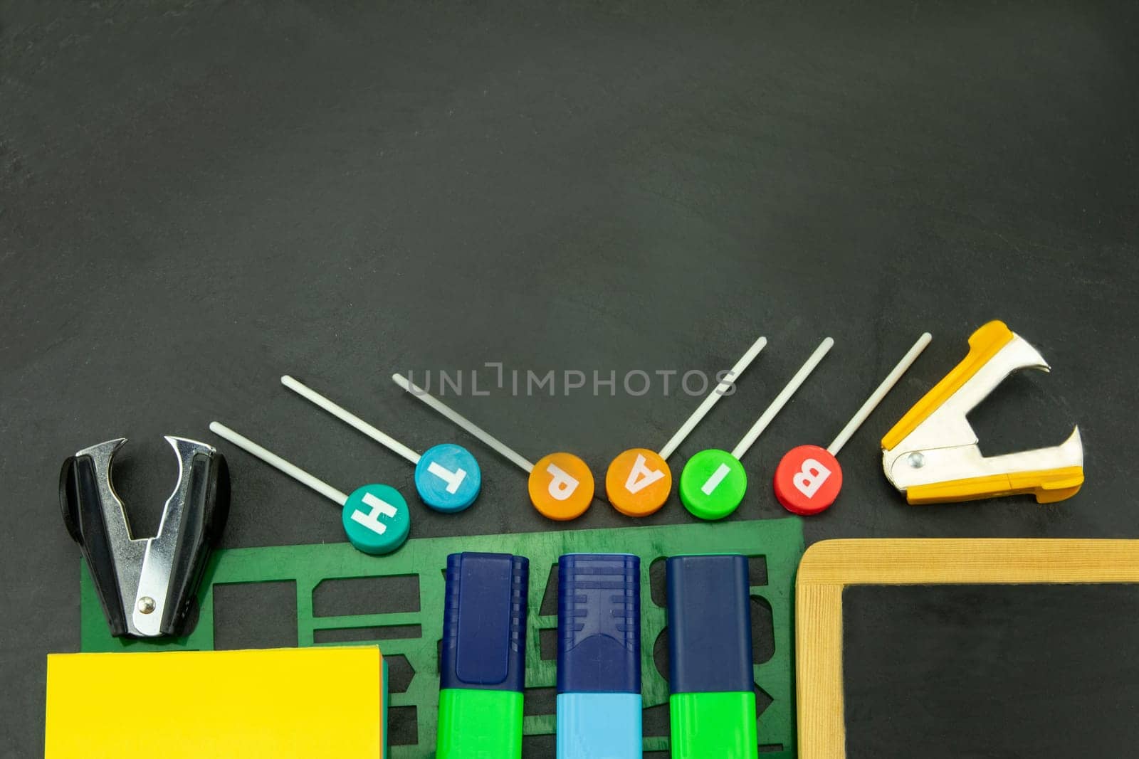 Closeup of colorful school supplies with copy space on blackboard background. Back to school.