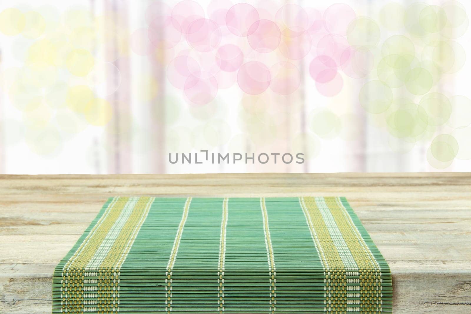 Empty table with green tablecloth over bright bokeh background. For your food and product display montage.
