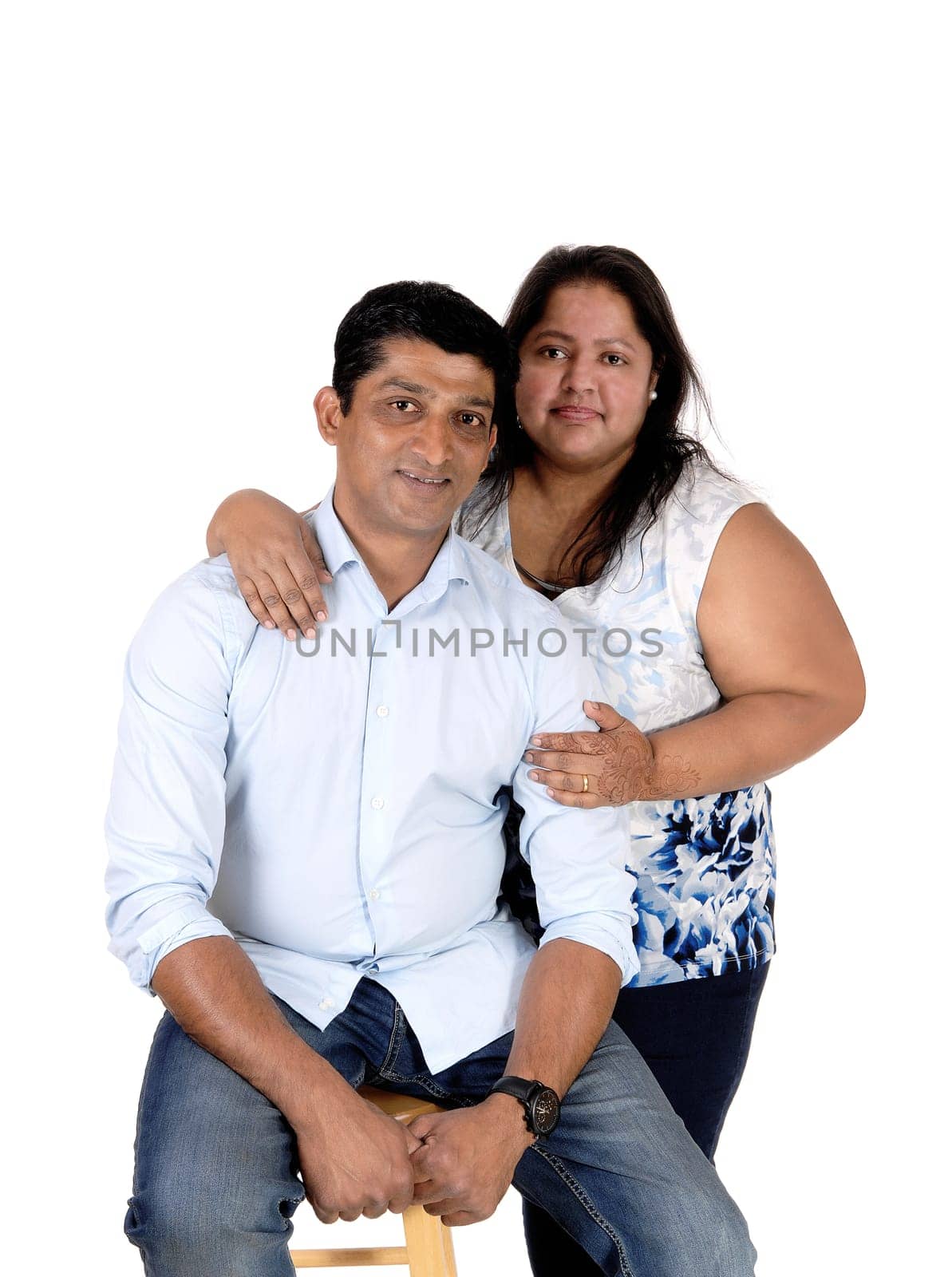 A middle age Asian couple in a close up image, the husband sitting and .the wife standing behind him, isolated for white background.