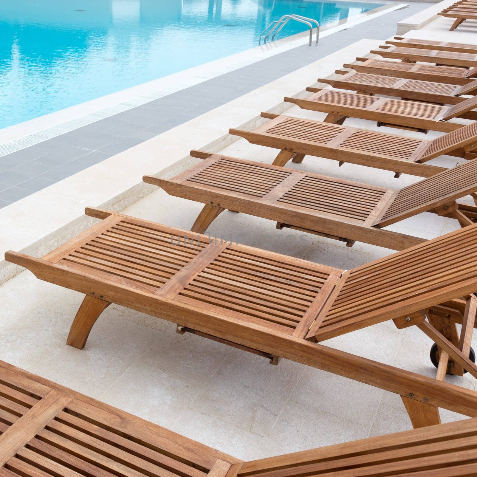Luxury modern swimming pool with wooden sunbeds