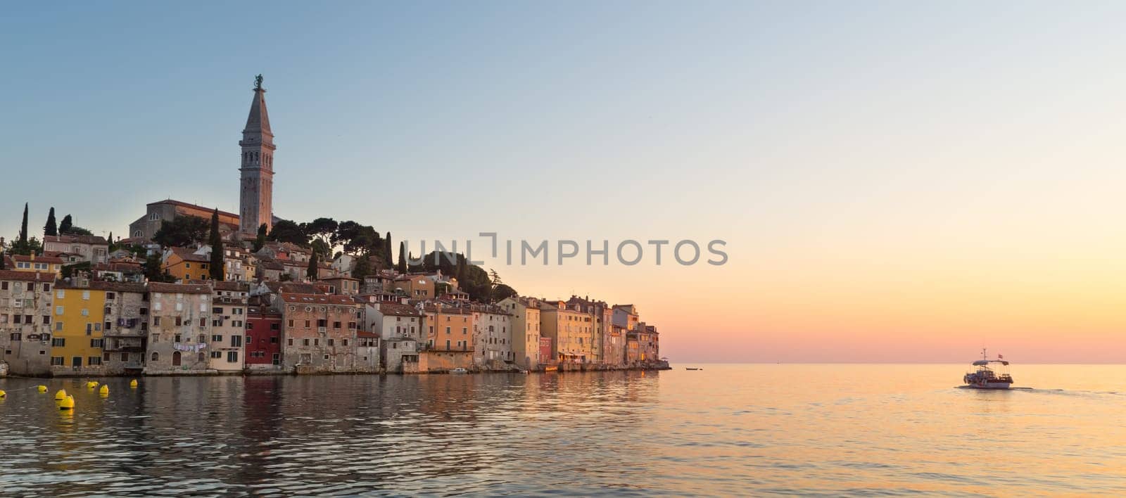 Colorful sunset of Rovinj town, Croatian fishing port on the west coast of the Istrian peninsula. Colorful evening seascape of Adriatic Sea. Traveling concept.