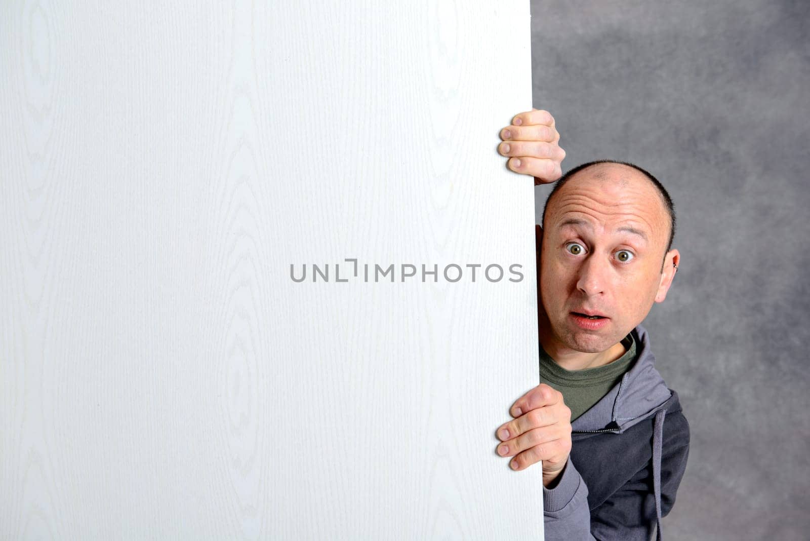 young man with a white advertising board in front of gray background