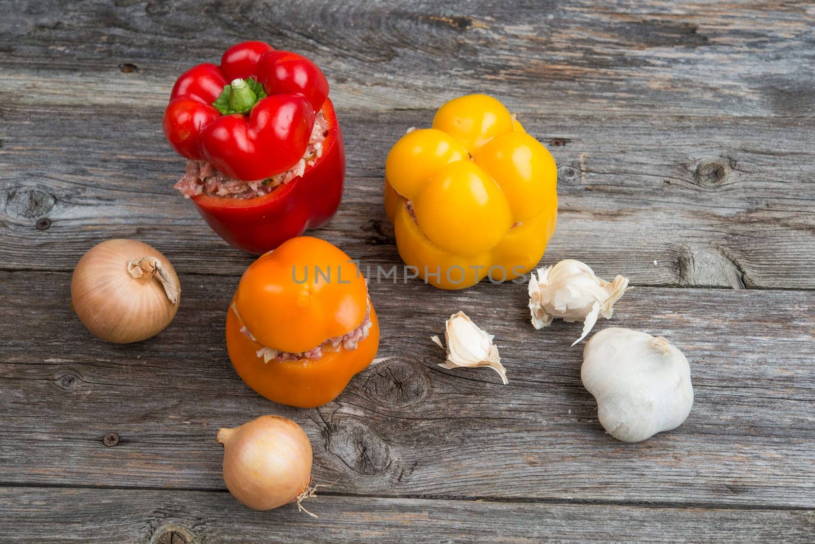 colorful filled pepper,garlic and onion on wooden ground