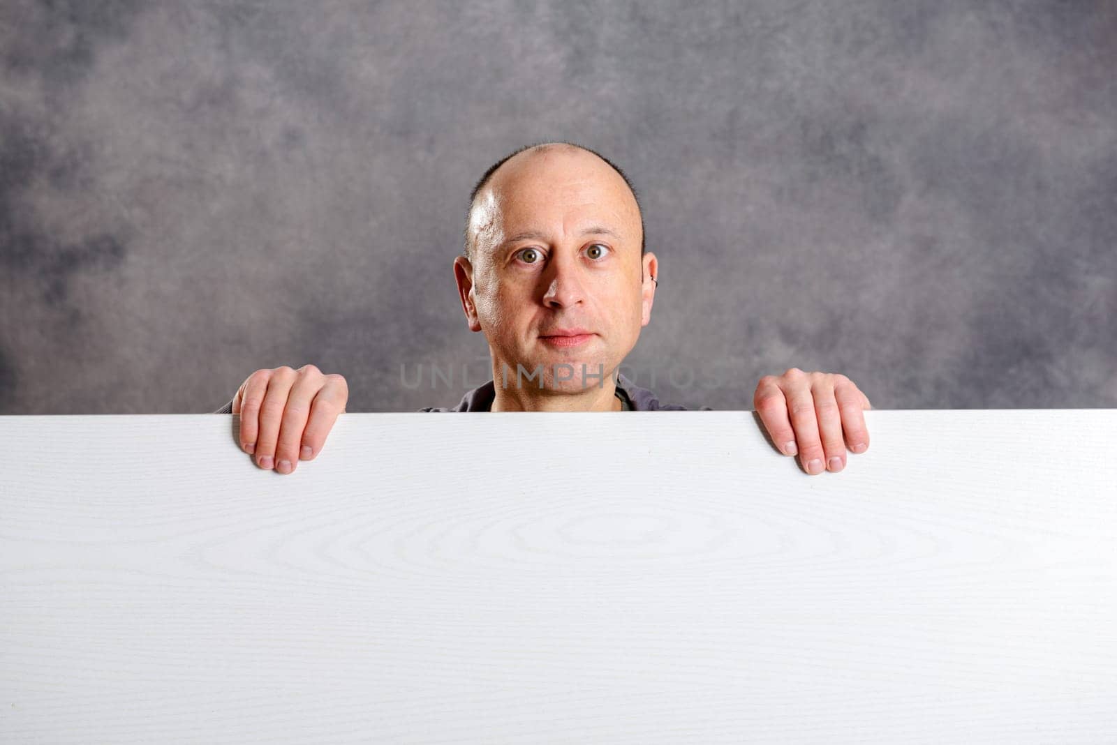 young man with a white advertising board in front of gray background
