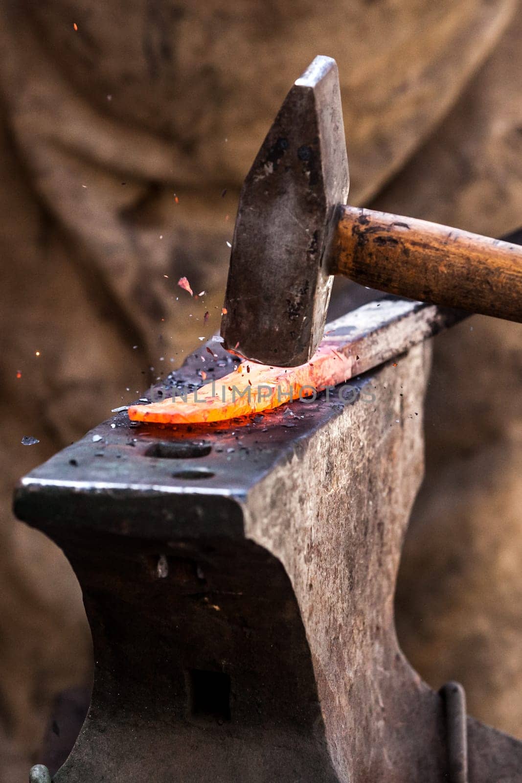 Blacksmith working on metal on anvil at forge detail shot