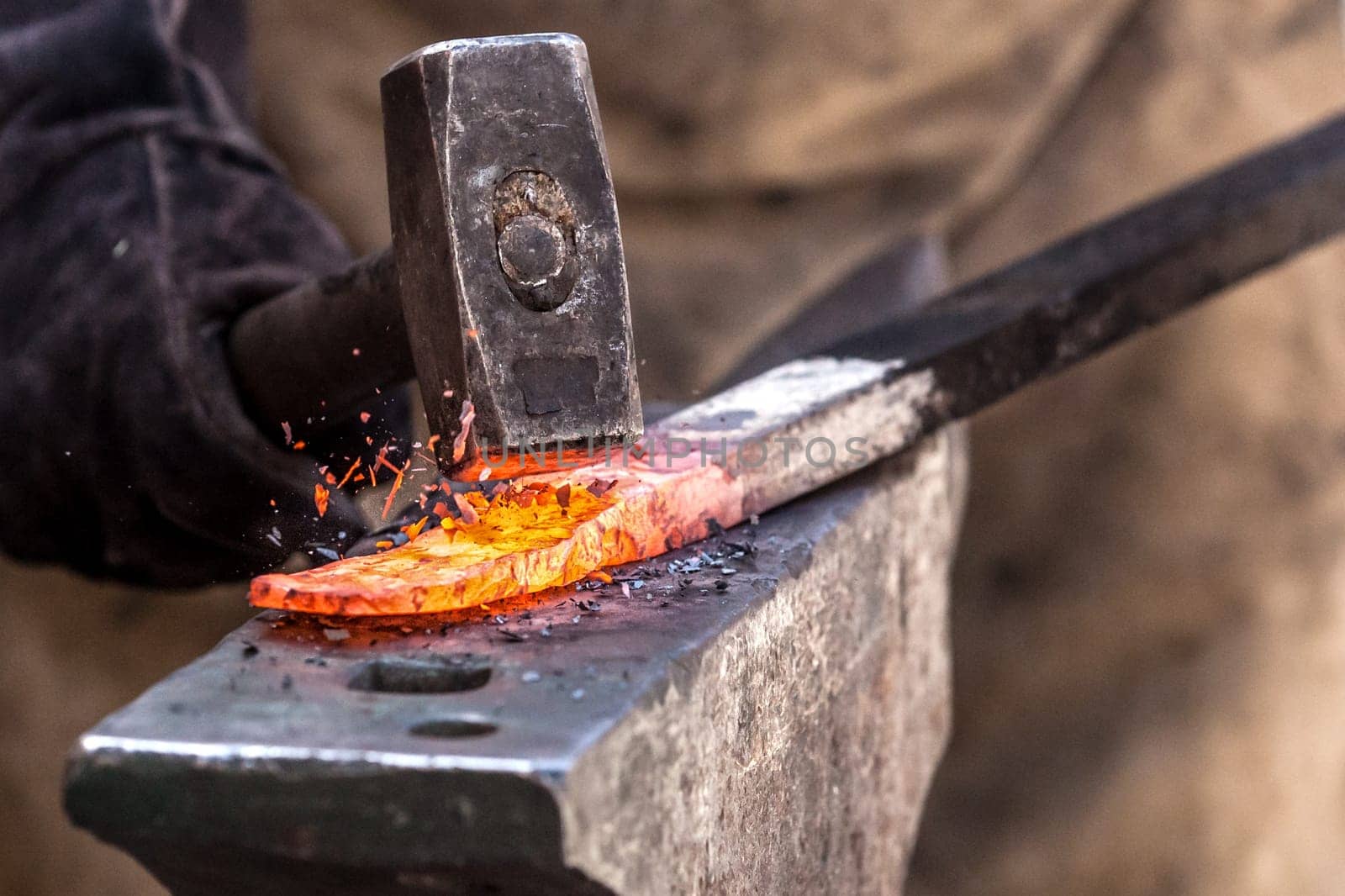 Blacksmith working on metal on anvil at forge high speed detail shot