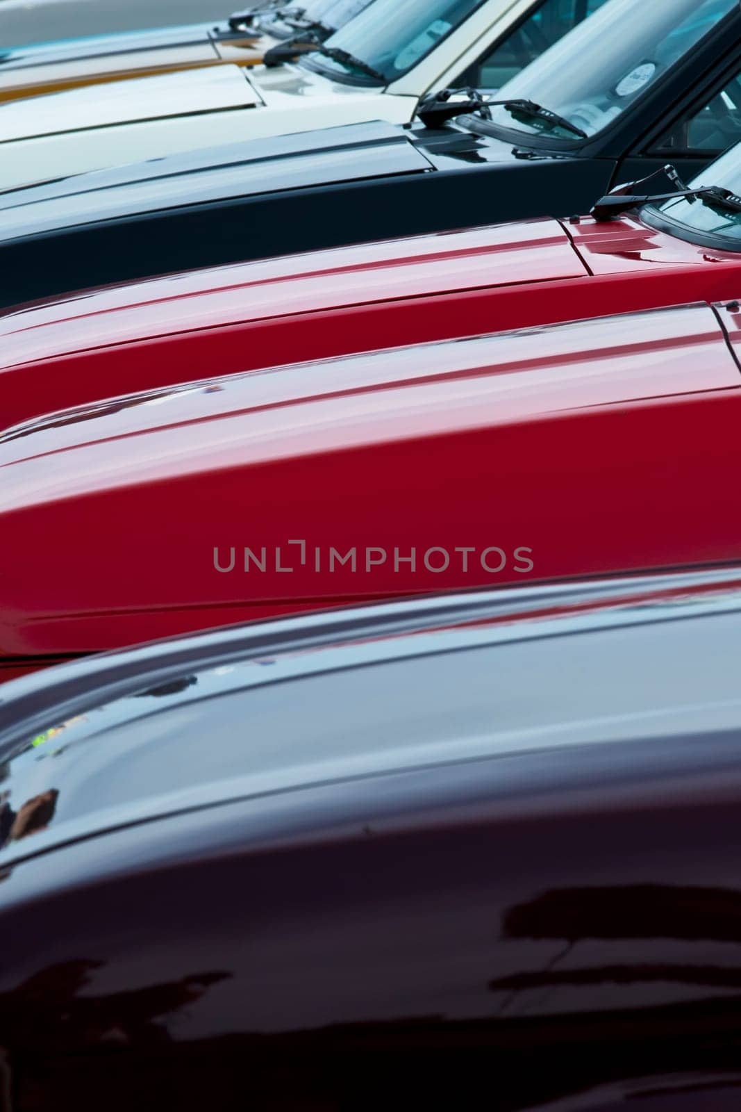 Abstract image showing linear patterns and colours on a row of cars parked next to eachother