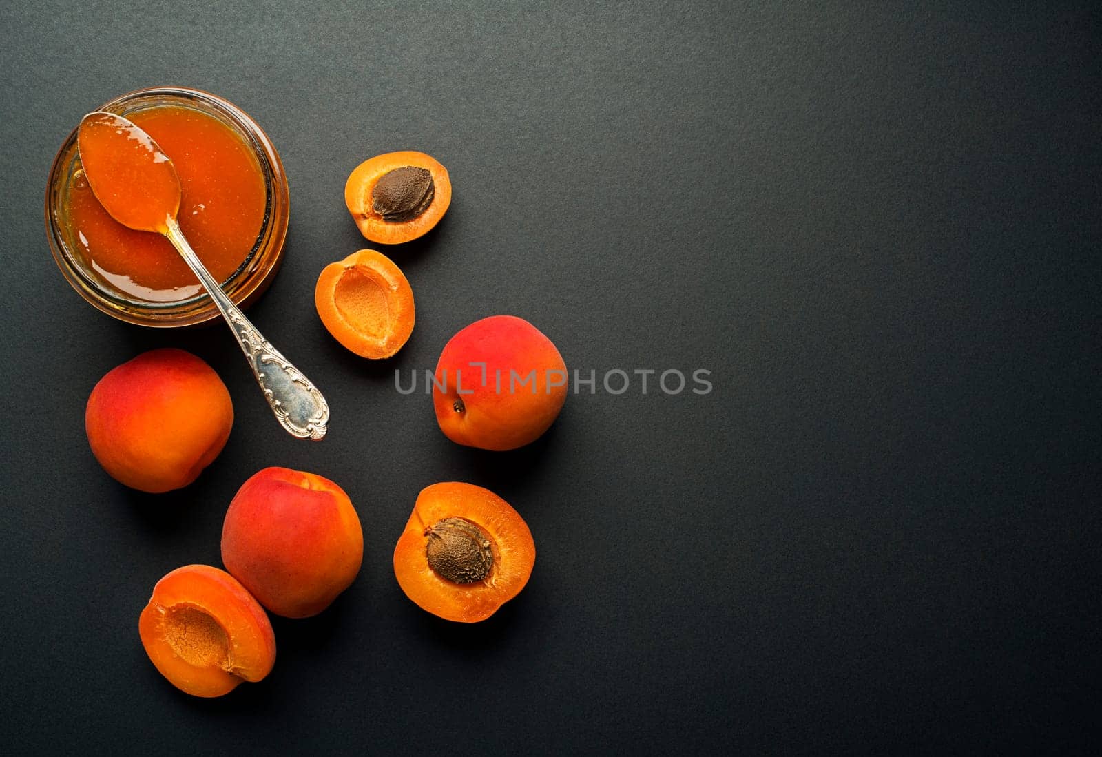 Apricot jam in a glass bowl with fruit around