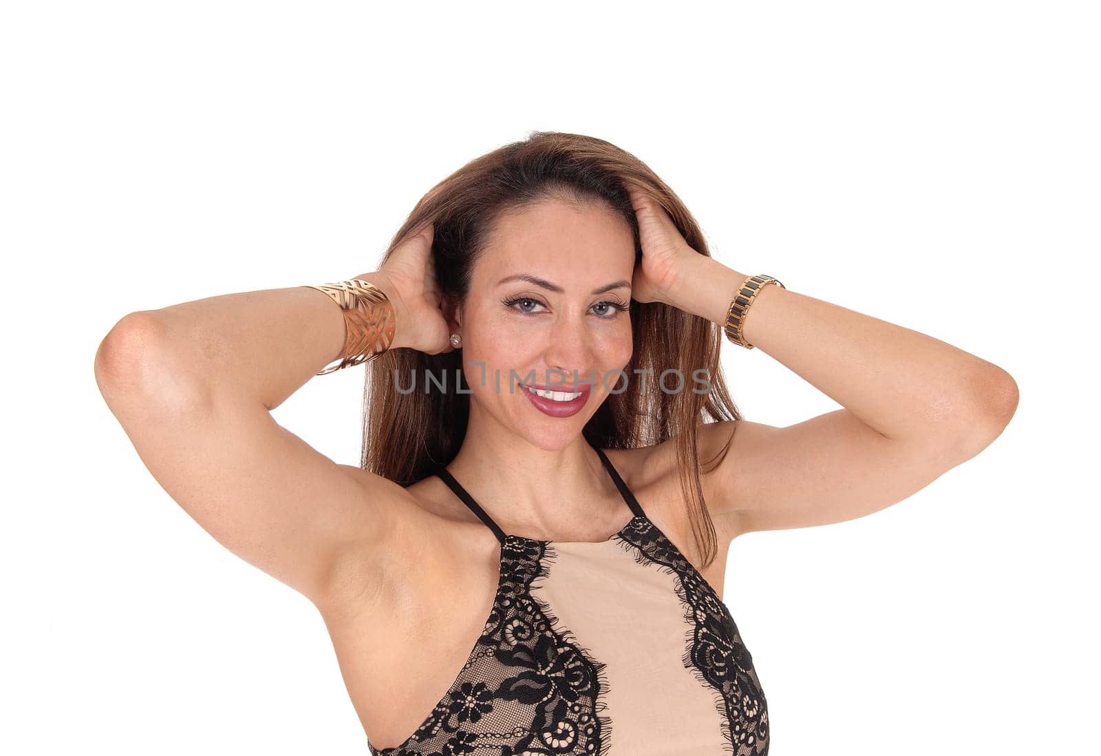 A young smiling woman standing from the front in a beige and black .blouse holding her hands behind her head, isolated for white background.