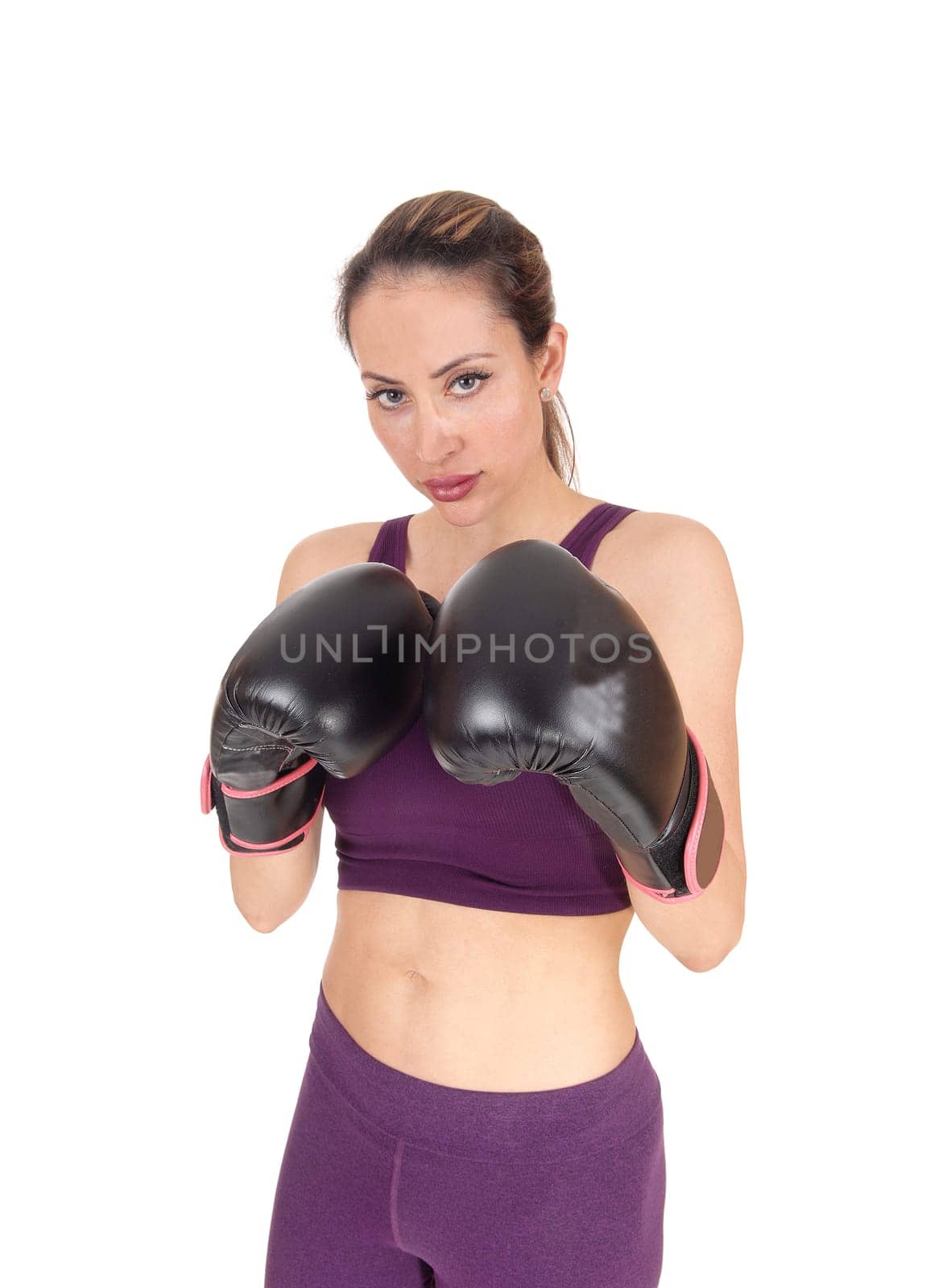 A beautiful woman serious looking with her arms up in black boxing .cloves ready to give a punch, isolated for white background.